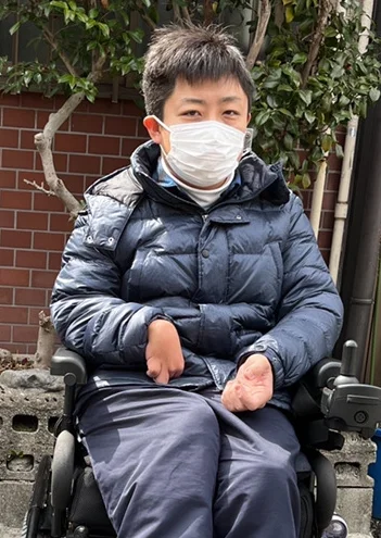 車椅子に乗りマスクをかけこちらを向いている多田宗一郎の写真