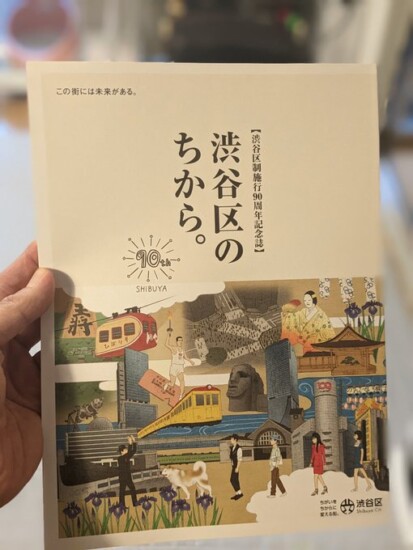 渋谷区制施行90周年記念誌「渋谷区のちから。」の表紙。上半分に大きくタイトルがあり、下半分にはモヤイ像、ハチ公などの渋谷の景色が描いてあります。