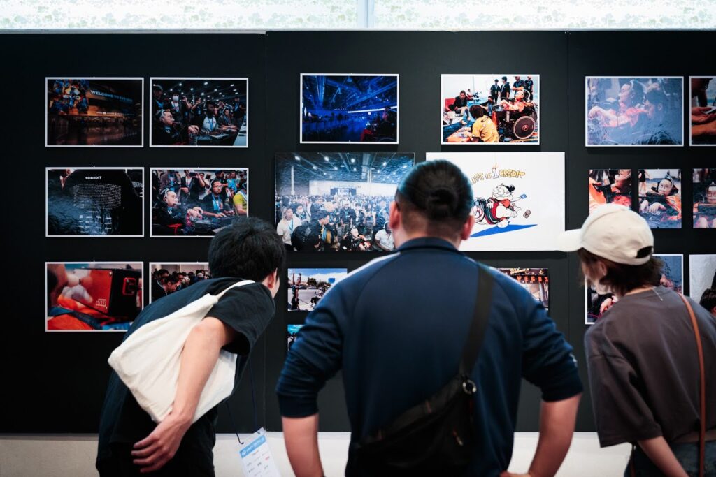 「EVO2024写真展」壁に貼られたたくさんの写真を見る来場者たちの様子