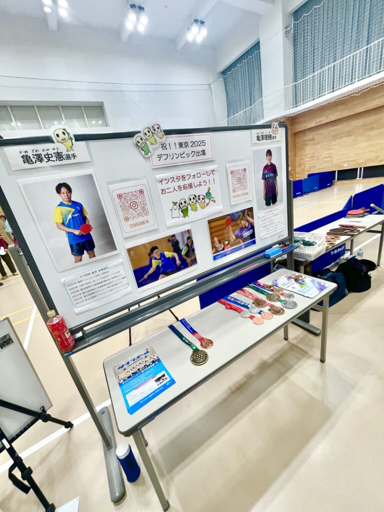亀澤理穂選手と亀澤史憲選手を紹介するボードの写真。プロフィールや写真、獲得したメダルが展示されている。