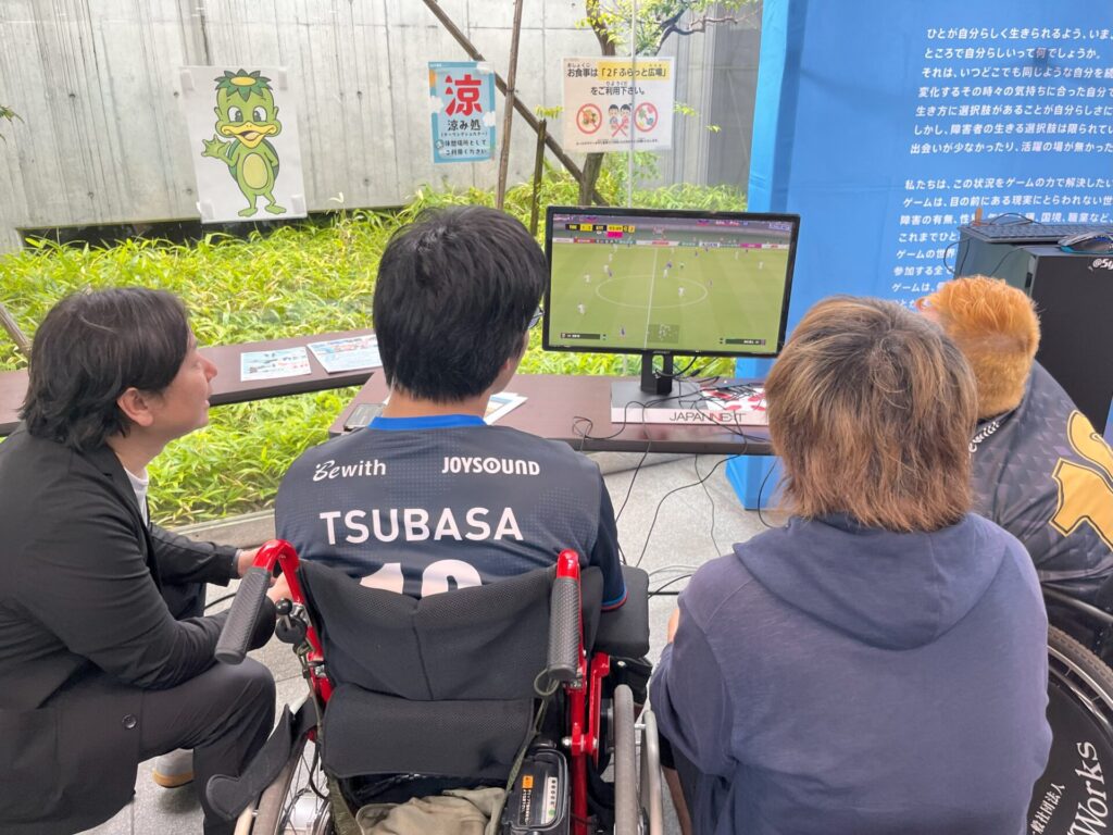イーパラユナイテッドのメンバーと井上マーさんが一緒にサッカーゲームをプレイする様子