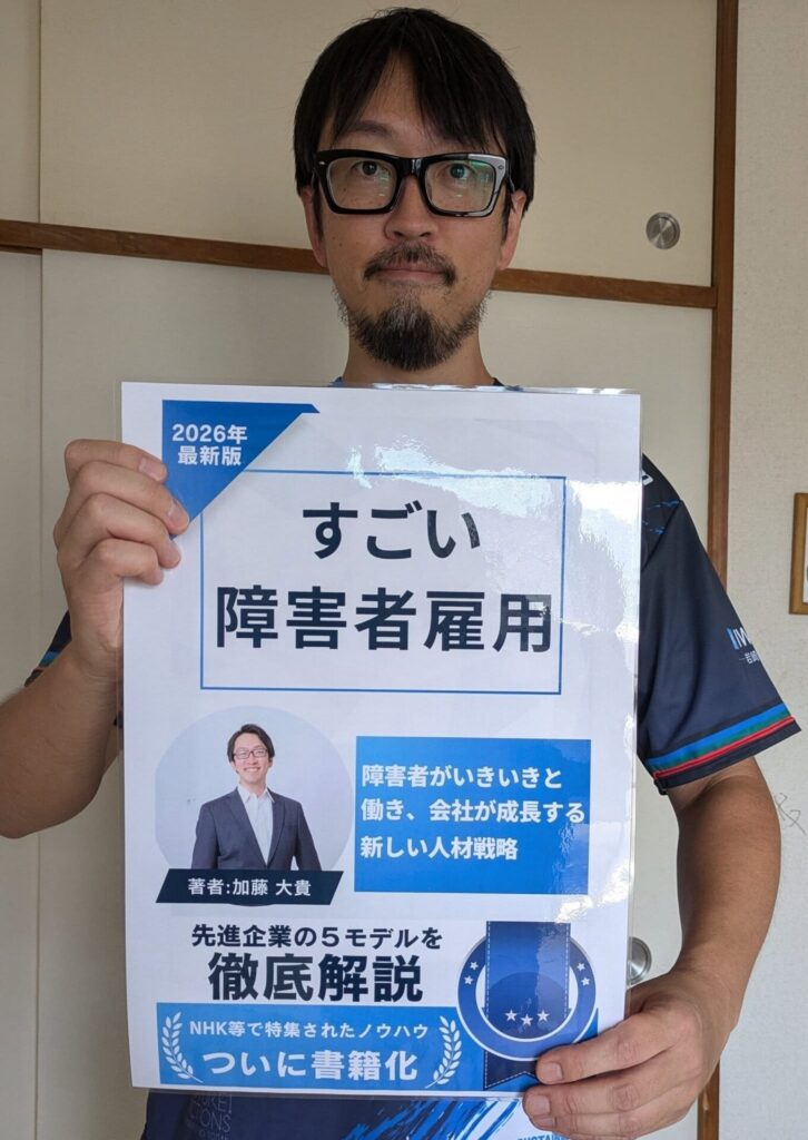 本の表紙のイメージ図を手に持つ加藤。タイトルは「すごい障害者雇用」、ほかに「2026年最新版」「障害者がいきいきと働き、会社が成長する新しい人材戦略」「著者 加藤大貴」「先進企業の5モデルを徹底解説」「NHK等で特集されたノウハウ ついに書籍化」と書かれている
