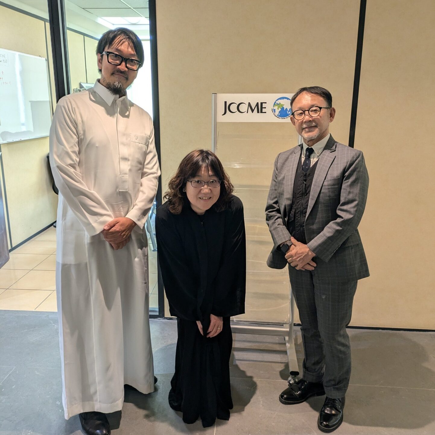 JCCMEと書かれたプレートの前に3人がこちらを向いて並んでいる
