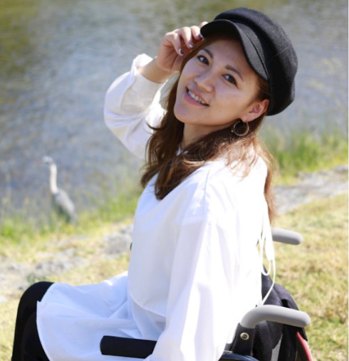黒い帽子を被りおしゃれな装いで車椅子に乗っている牧野美保の写真