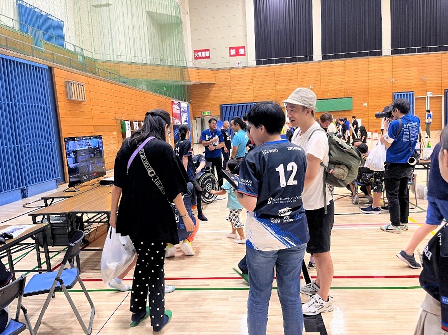 イーパラのユニフォームを着たasaseが来場者と話す様子