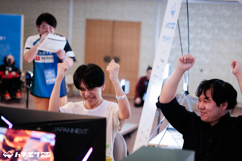 両手を挙げてガッツポーズするトーナメント参加者