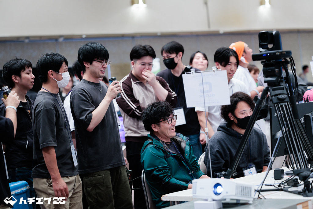 対戦中の参加者と後ろで観戦する大勢の観客たち