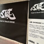 黒字に白文字で「心眼」大きく書かた下に「Road to Saudi 2030」と書かれた特大パネルと、心眼プロジェクトの説明文の書かれたパネルの写真
