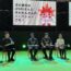 ステージ上で4人が並んで椅子2座っている様子。背後の大きい画面に「次の演目は、ePARAさんと みらせんさんの トークショーです」と表示されている