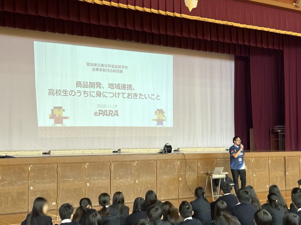 体育館で学生たちを前にプレゼンテーションを行う加藤