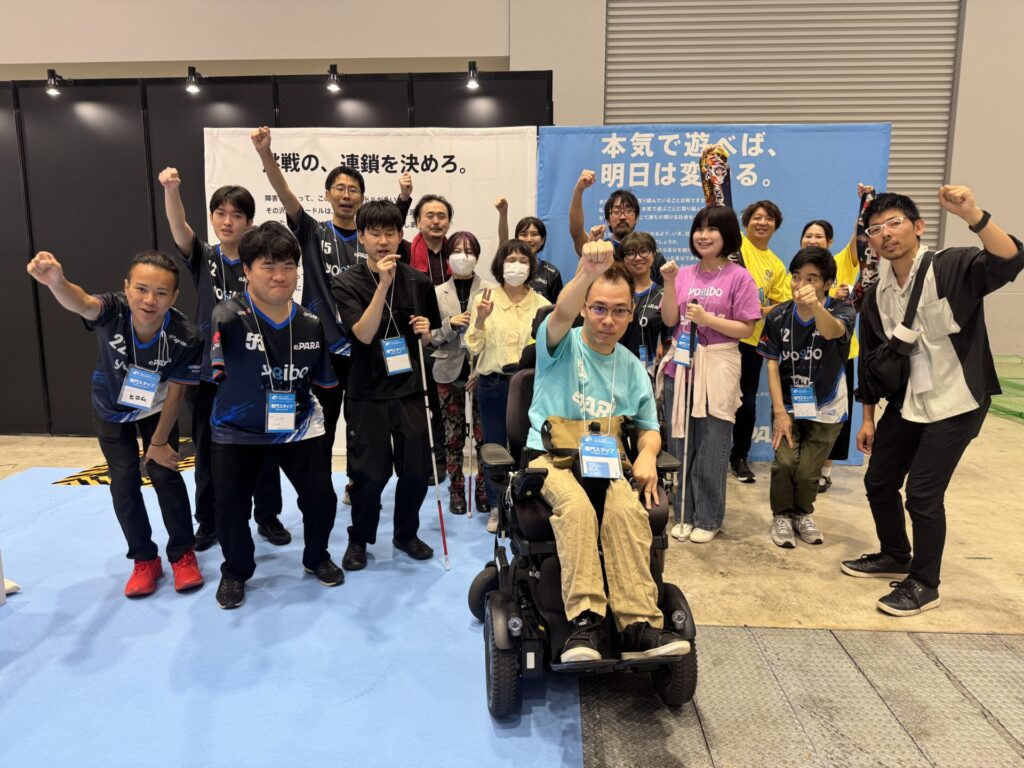 20人ほどの集合写真。それぞれ拳を突き上げるなどポーズを取っている