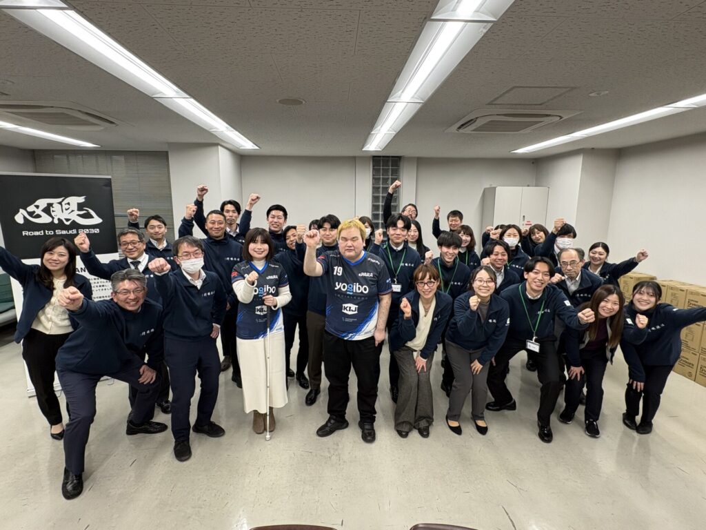 30人ほどの集合写真。皆笑顔で拳をあげている