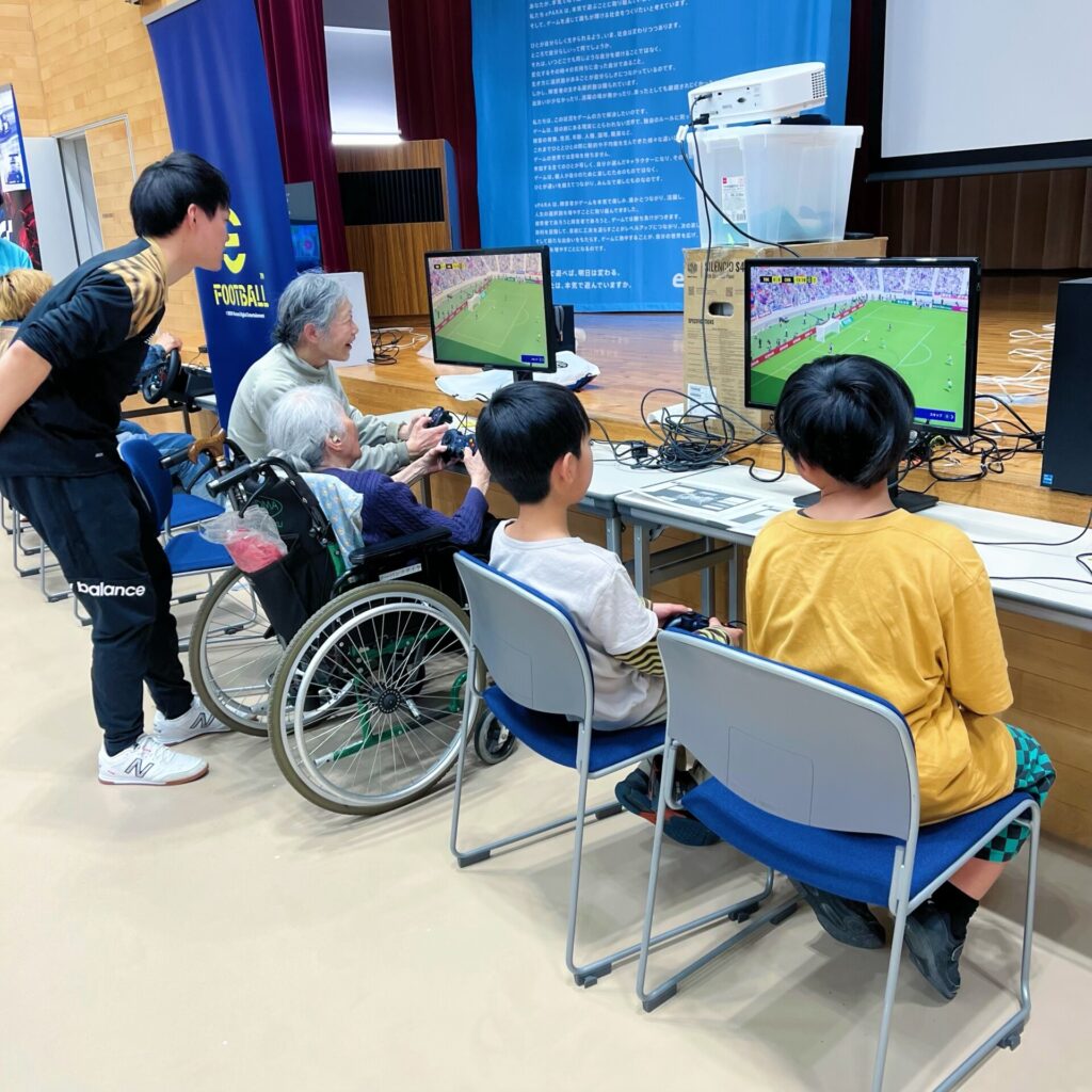 高齢者や子どもがサッカーゲームをプレイする様子