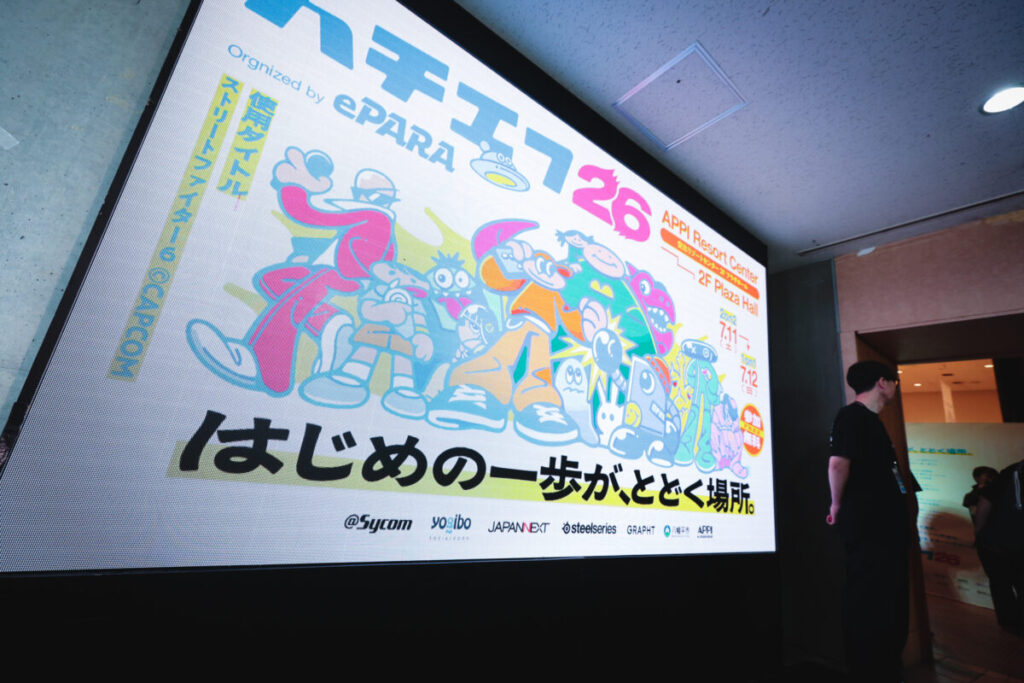 「はじめの一歩が、とどく場所。」と書かれたキービジュアルのスクリーンの写真。